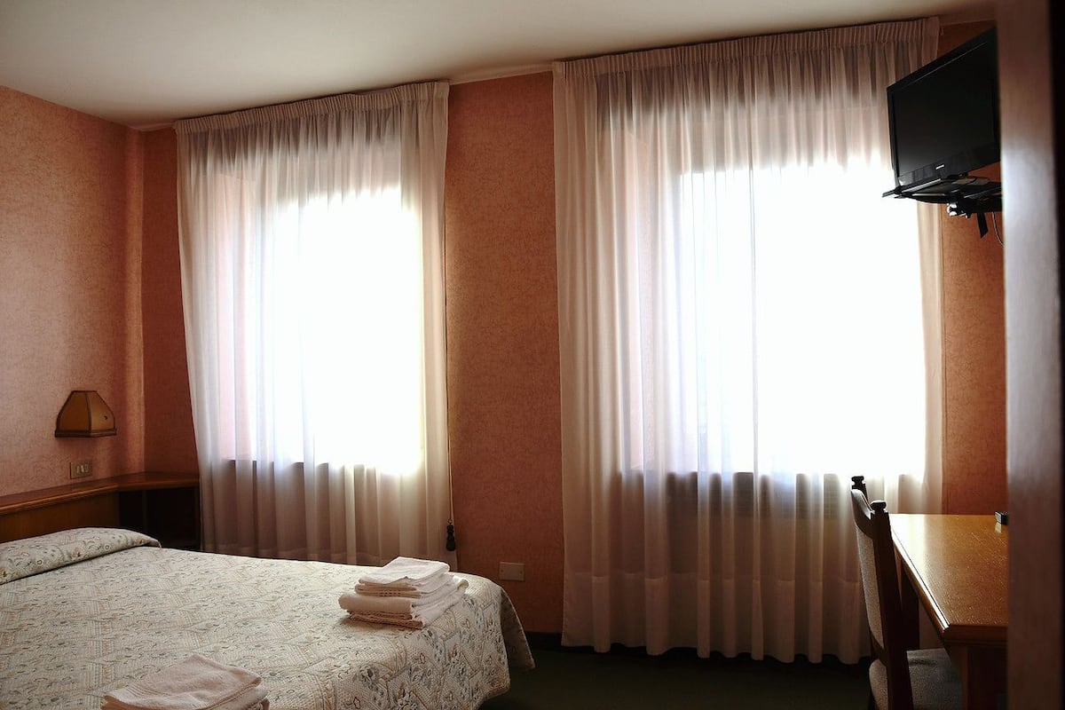 A hotel room with a bed, a desk, and a television.