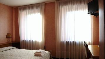 A hotel room with a bed, a desk, and a television.