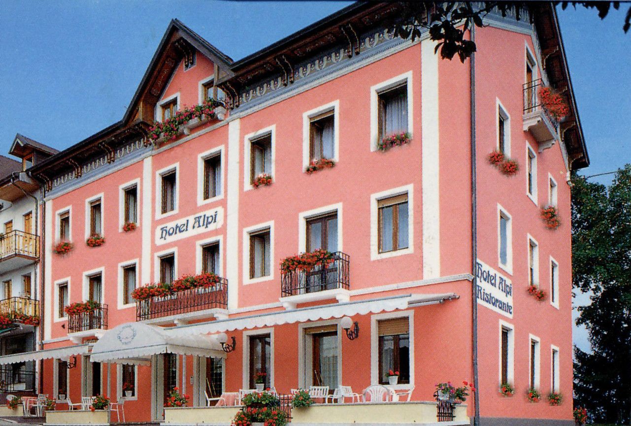 A pink building with multiple windows and balconies, labeled "Hotel Alpen."