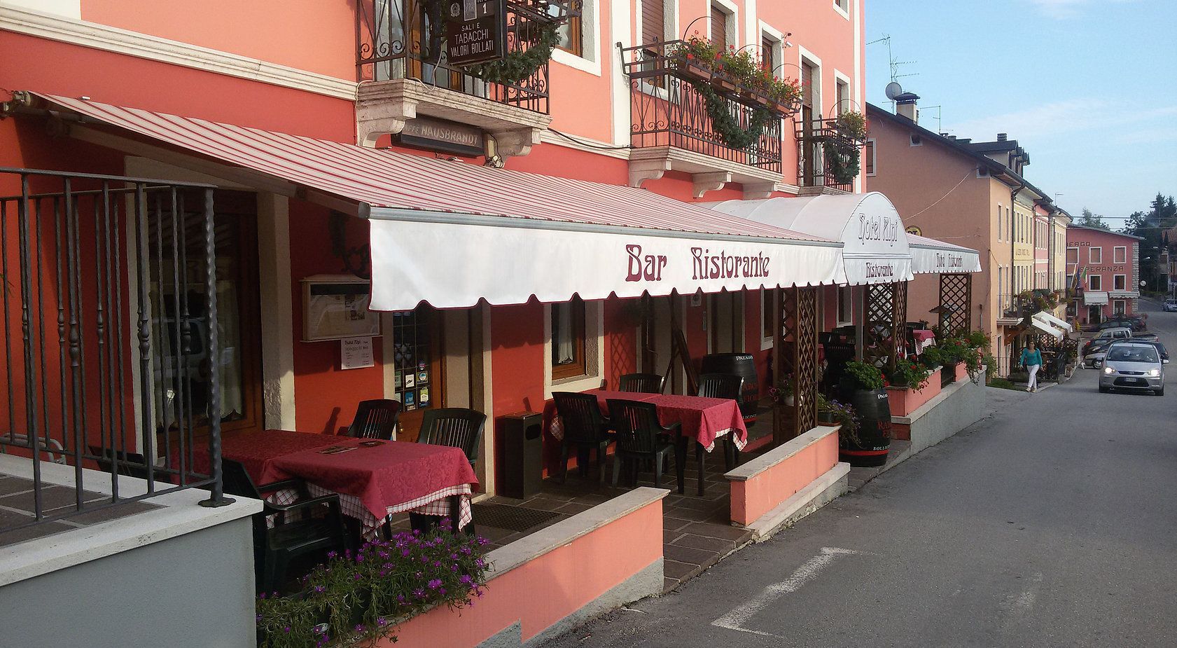 A Bar Ristorante with outdoor seating, a red awning, and a street view.