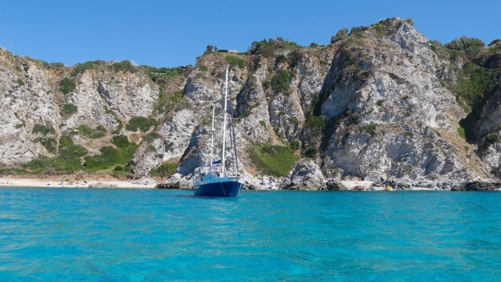 Un bateau était amarré près d’une côte rocheuse, dans une eau d’un bleu limpide.