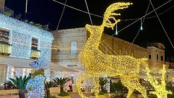 Un patio con una gran escultura iluminada de ciervo, plantas en macetas y un edificio con luces.