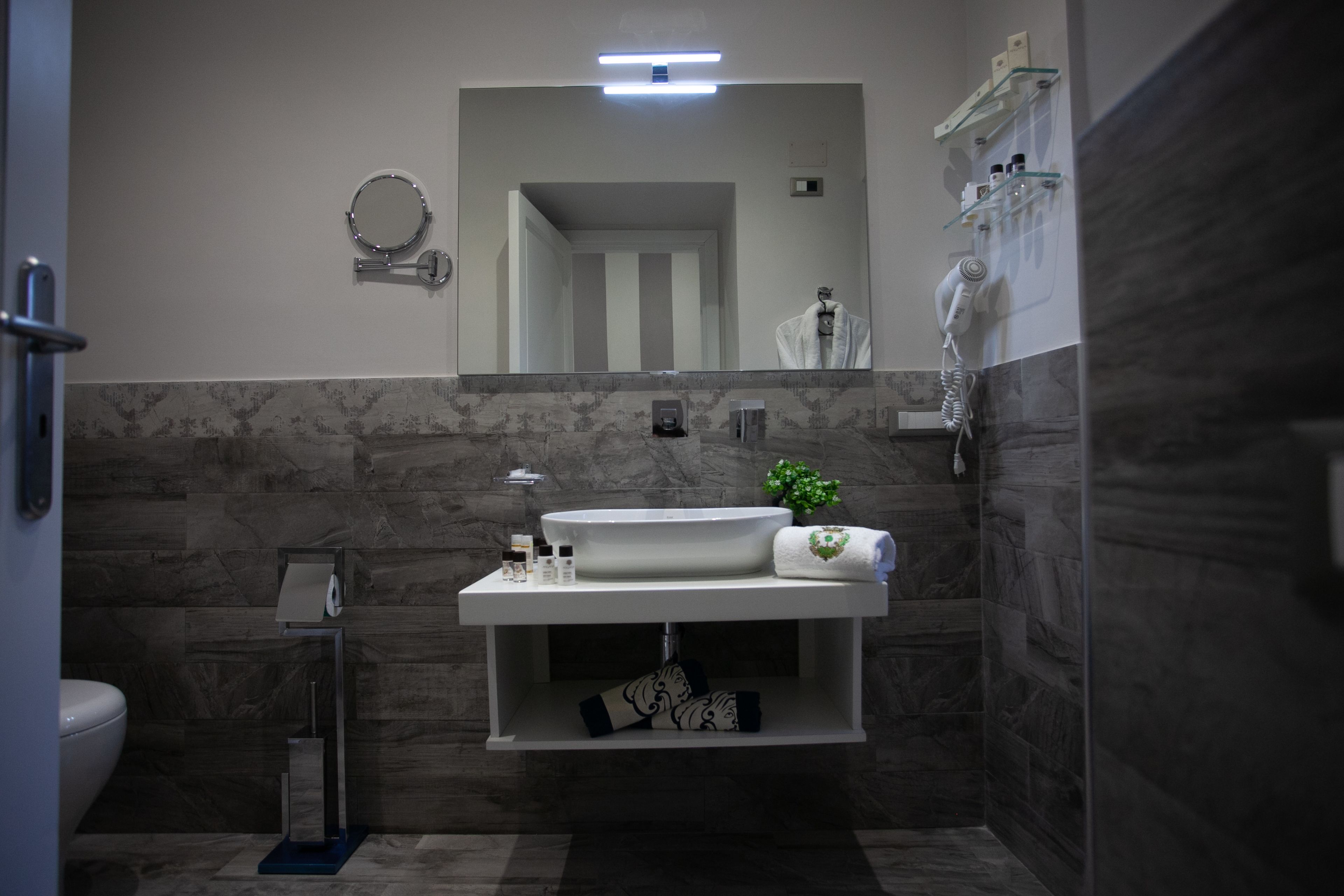 A modern bathroom with a large mirror, a sink, and a towel rack.