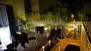 An outdoor seating area with metal chairs and tables, a decorative railing, and potted plants. - Residenza Le due Sicilie (Tropea)