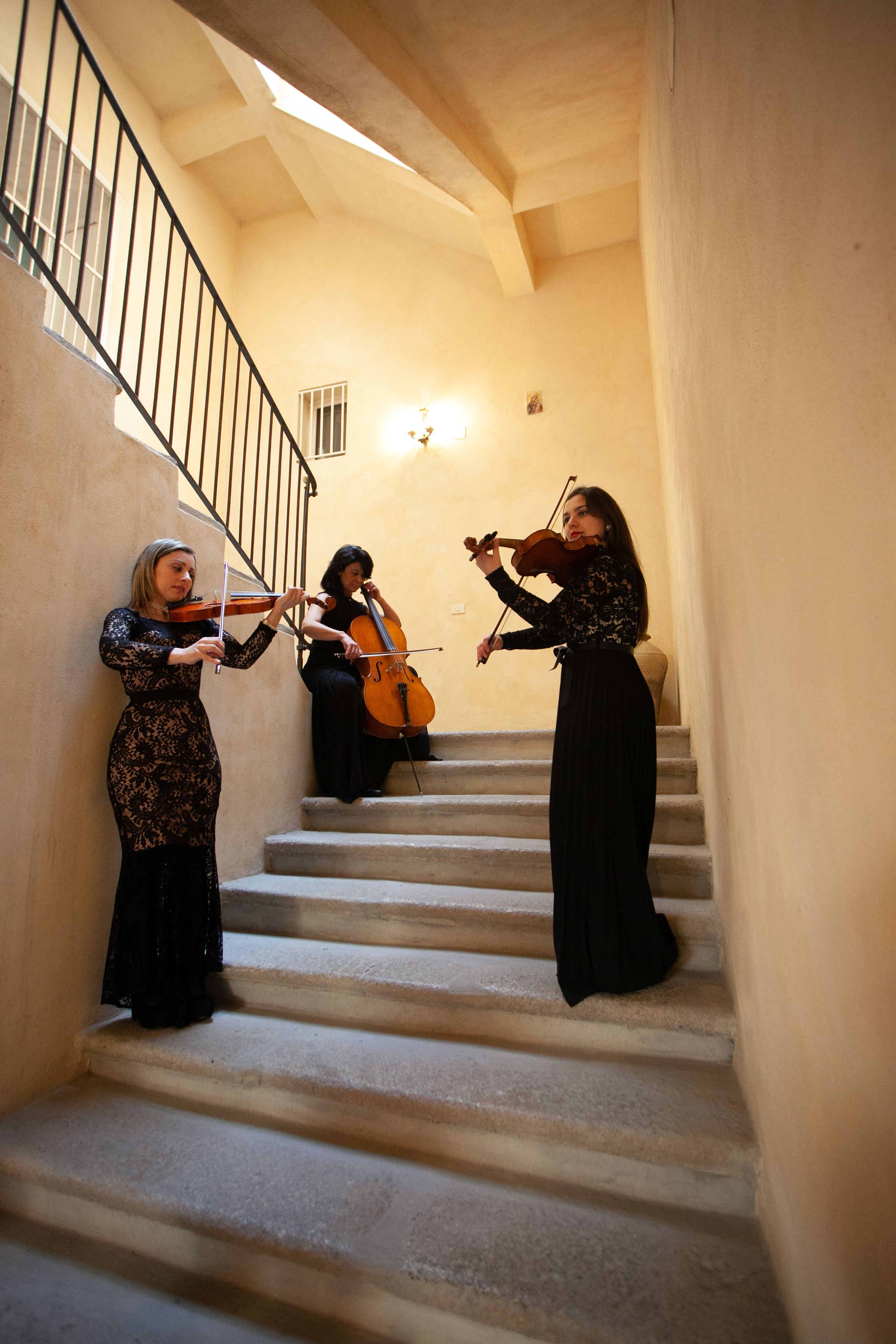 A staircase with three individuals playing violins.