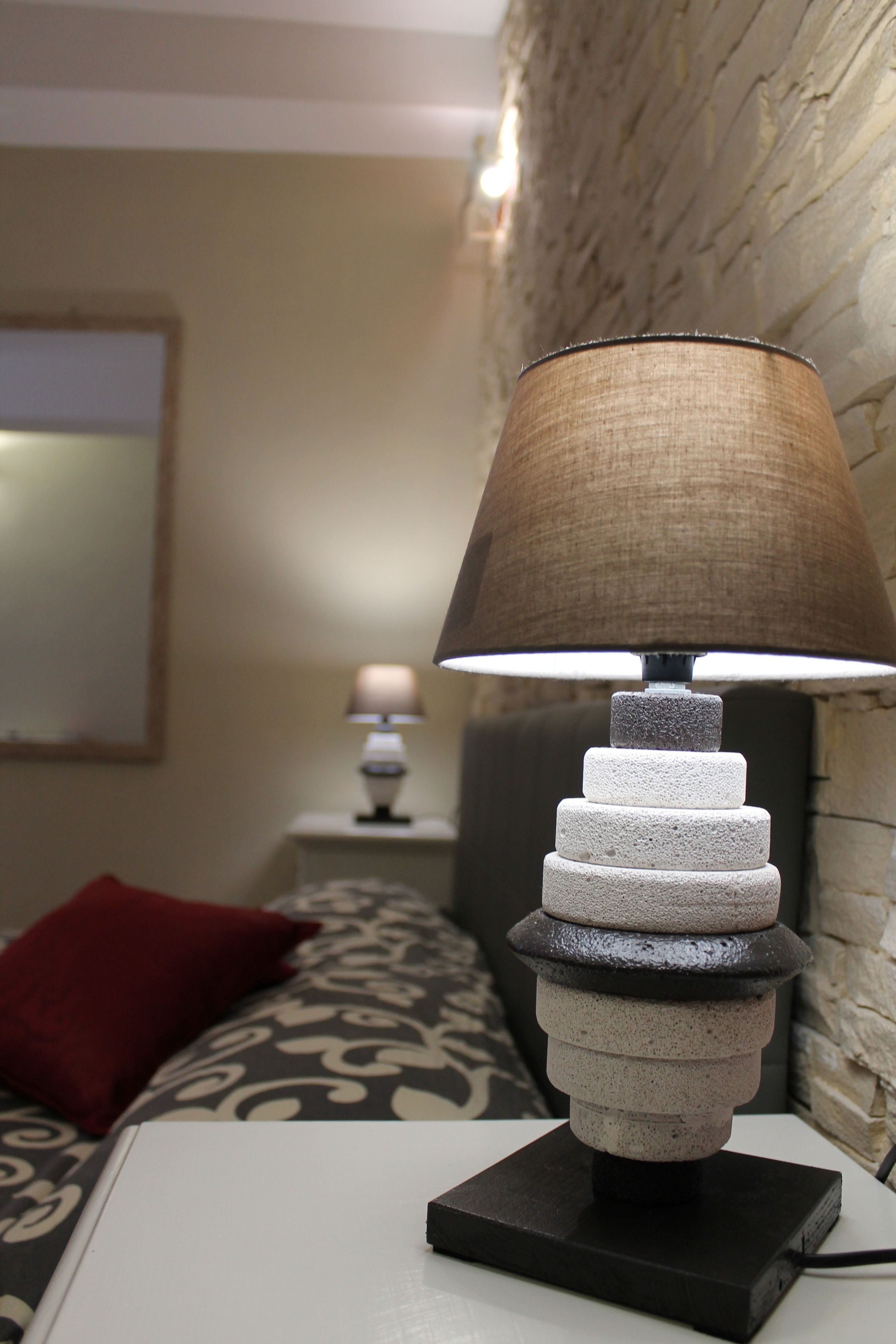 Une lampe moderne, dotée d’un abat-jour texturé, posée sur une table de chevet dans une chambre d’hôtel.
