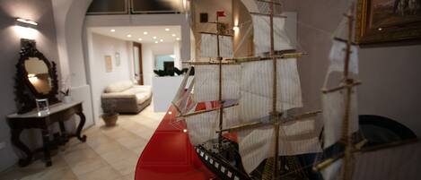 A model ship in a room with an arched ceiling and a framed picture on the wall.
