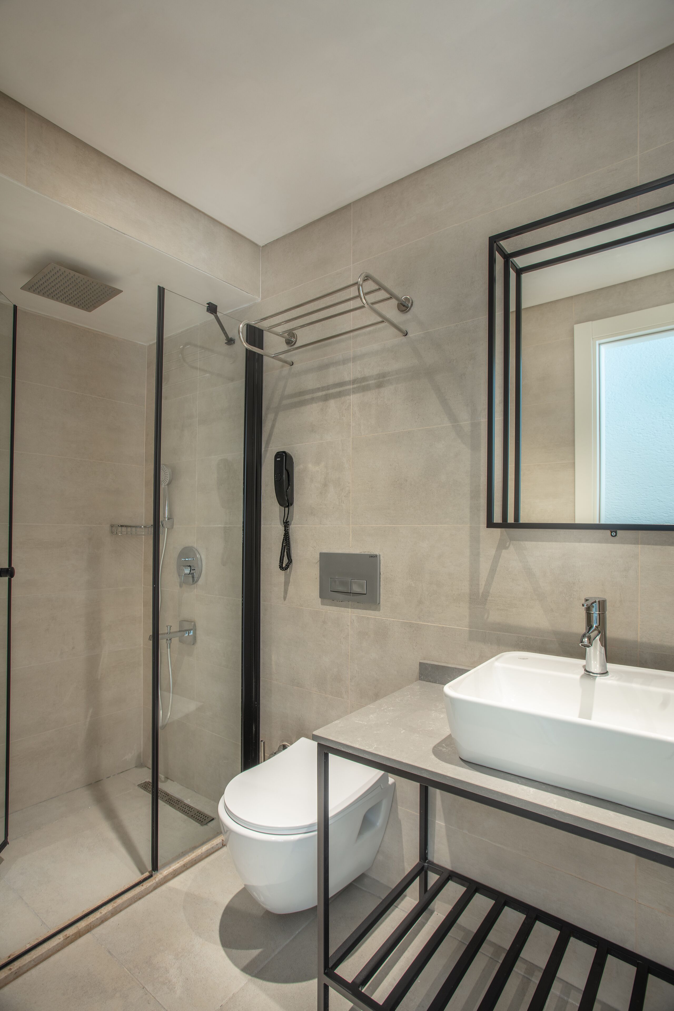 A modern bathroom with a glass shower enclosure, a white toilet, and a large mirror above a white sink.
