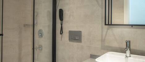 A modern bathroom with a glass shower enclosure, a white toilet, and a large mirror above a white sink.