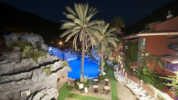 A hotel with a pool area, palm trees, and outdoor seating.