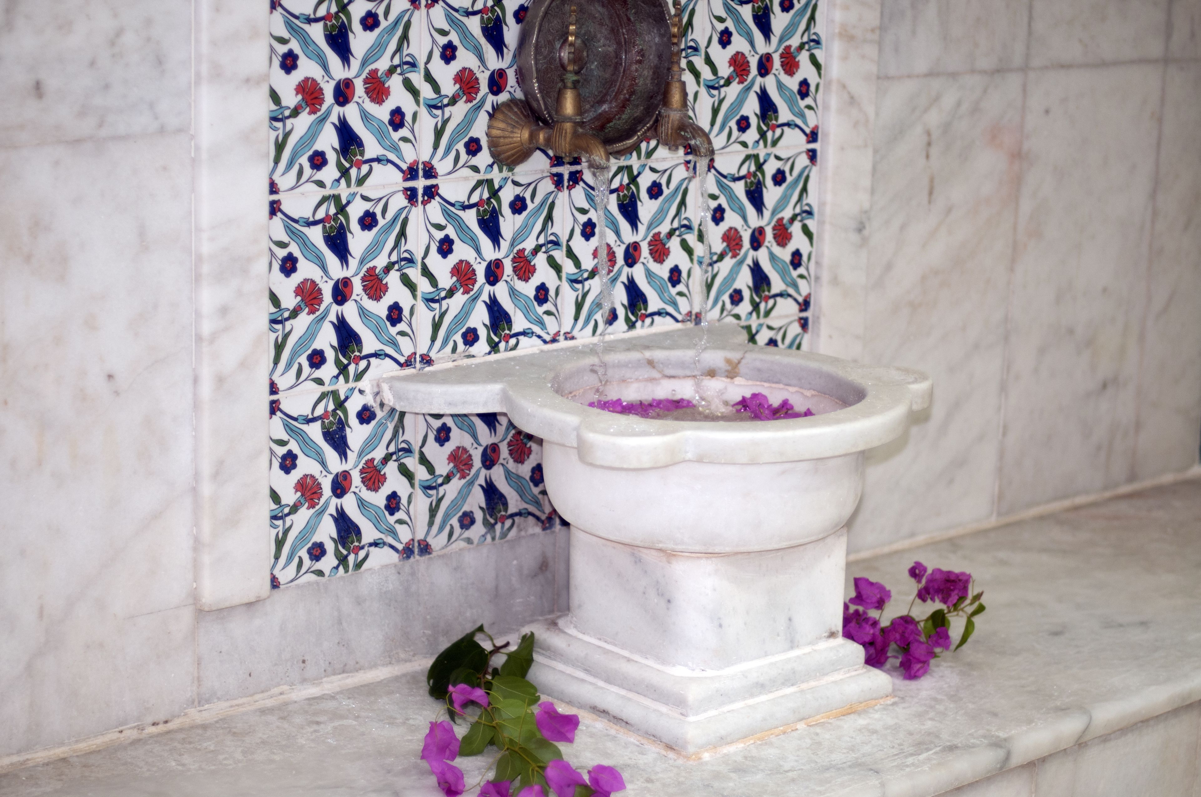 A bathroom with a toilet, a decorative wall tile, and a marble floor.