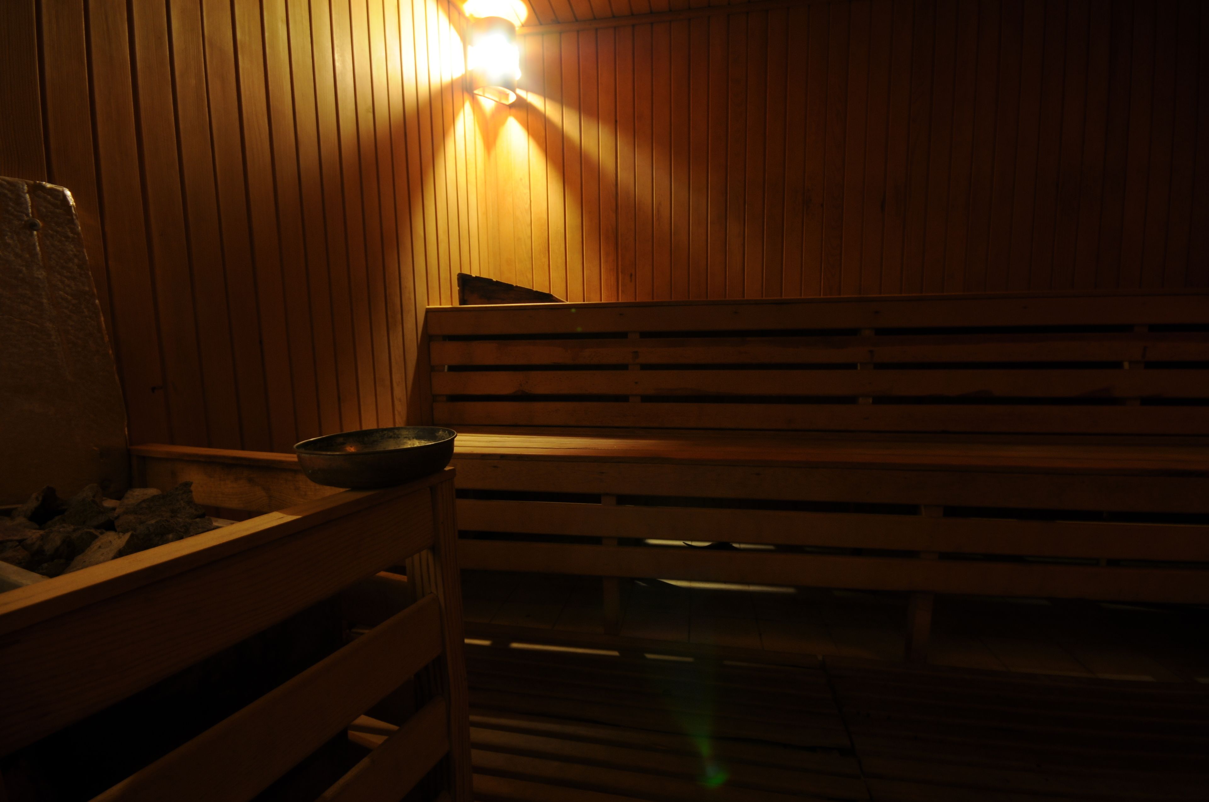 A wooden bench in a sauna with a bowl and a towel on it.