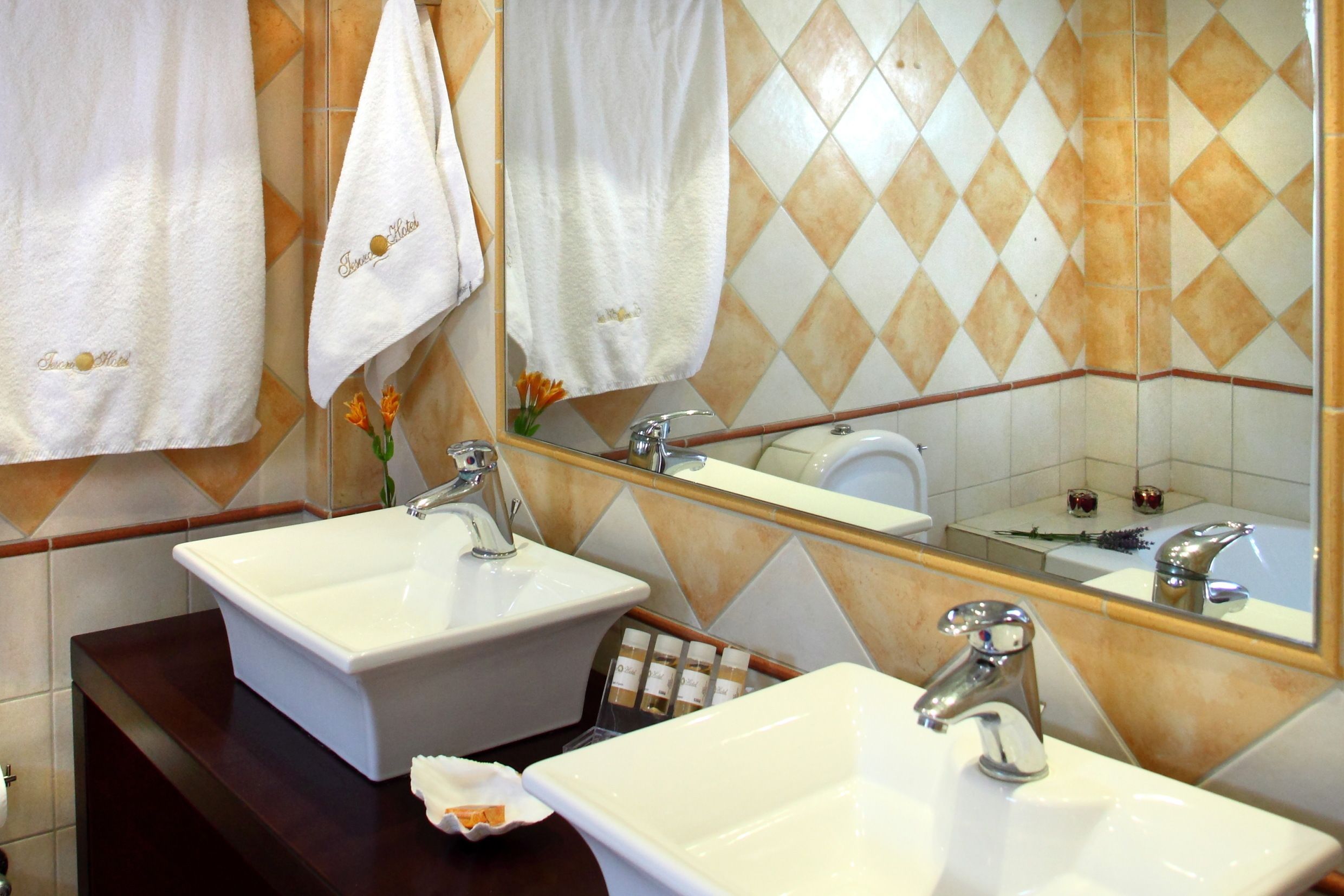 Ein Badezimmer mit zwei Waschbecken, einem Spiegel und Handtüchern, die an der Wand hängen.