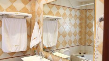 Un baño con dos lavamanos, un espejo grande y un perchero para toallas.