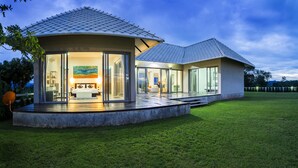 Una casa moderna con un gran ventanal que da a un dormitorio, un patio y vistas del paisaje.