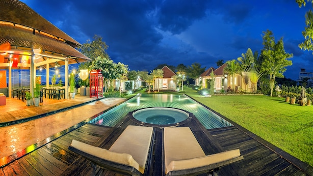 Un área de piscina con jacuzzi, mobiliario exterior y un porche cubierto.