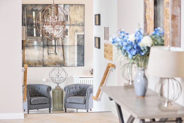 Un interior moderno con un sillón gris, un globo decorativo y una mesa con un jarrón de flores.