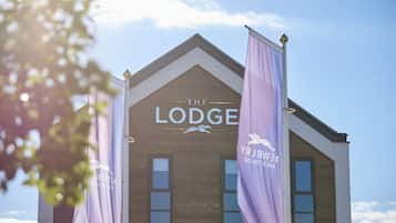 Un edificio con un cartel que dice "The Lodge" y dos banderines morados con letras blancas.