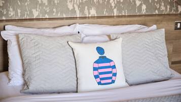 Ein ordentlich bezogenes Bett mit vielen Kissen, darunter eines mit einem grafischen Design.