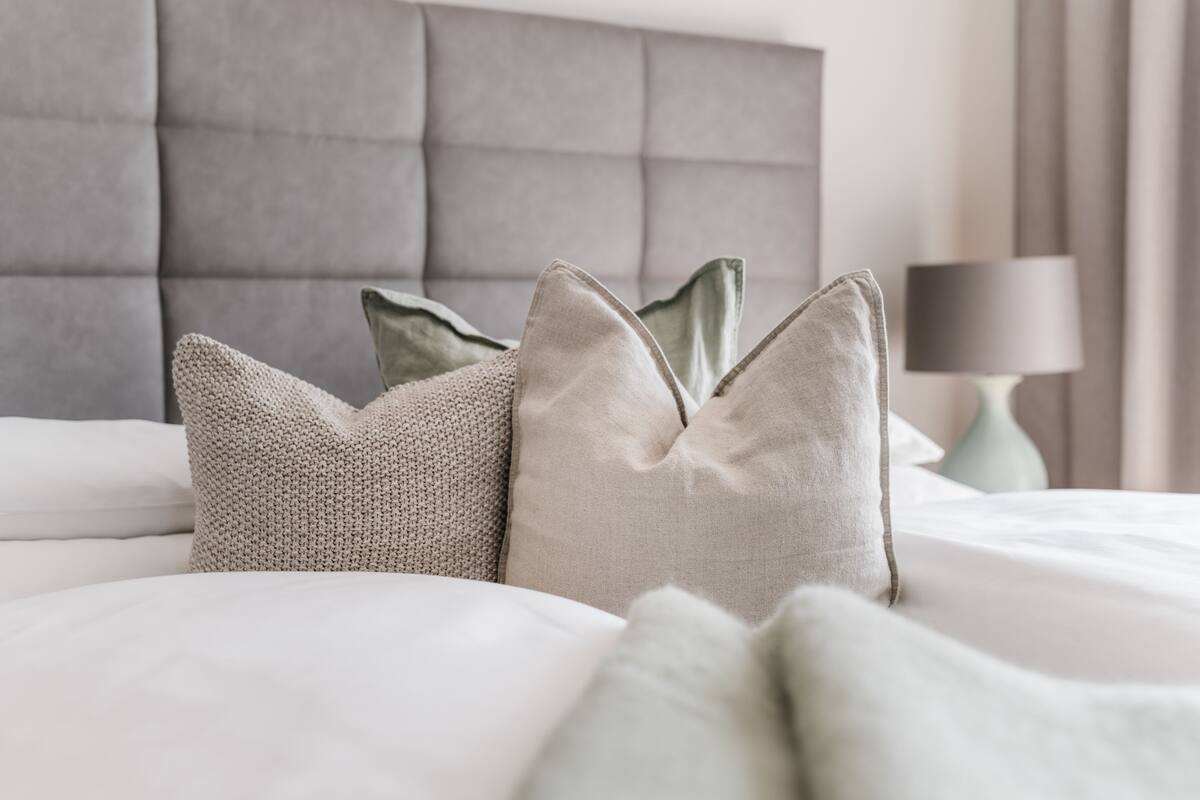 A neatly made bed with a tufted headboard and decorative pillows.