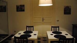 A dining area with two tables and chairs, a hanging light fixture, and two framed pictures on the walls. - A Casa di Giuseppe (Palermo)