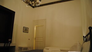 A hotel room with a bed, a bedside table, a chair, a door, and a chandelier. - A Casa di Giuseppe (Palermo)