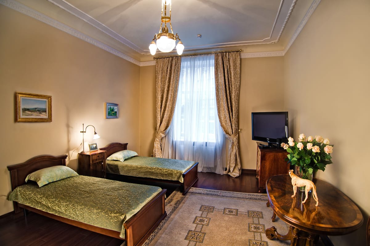 Una habitación de hotel con dos camas, un televisor, un florero con flores y un candelabro.