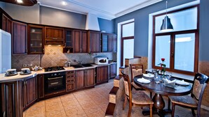Una cocina moderna con armarios de madera oscura, horno empotrado y comedor con mesa preparada para cuatro.