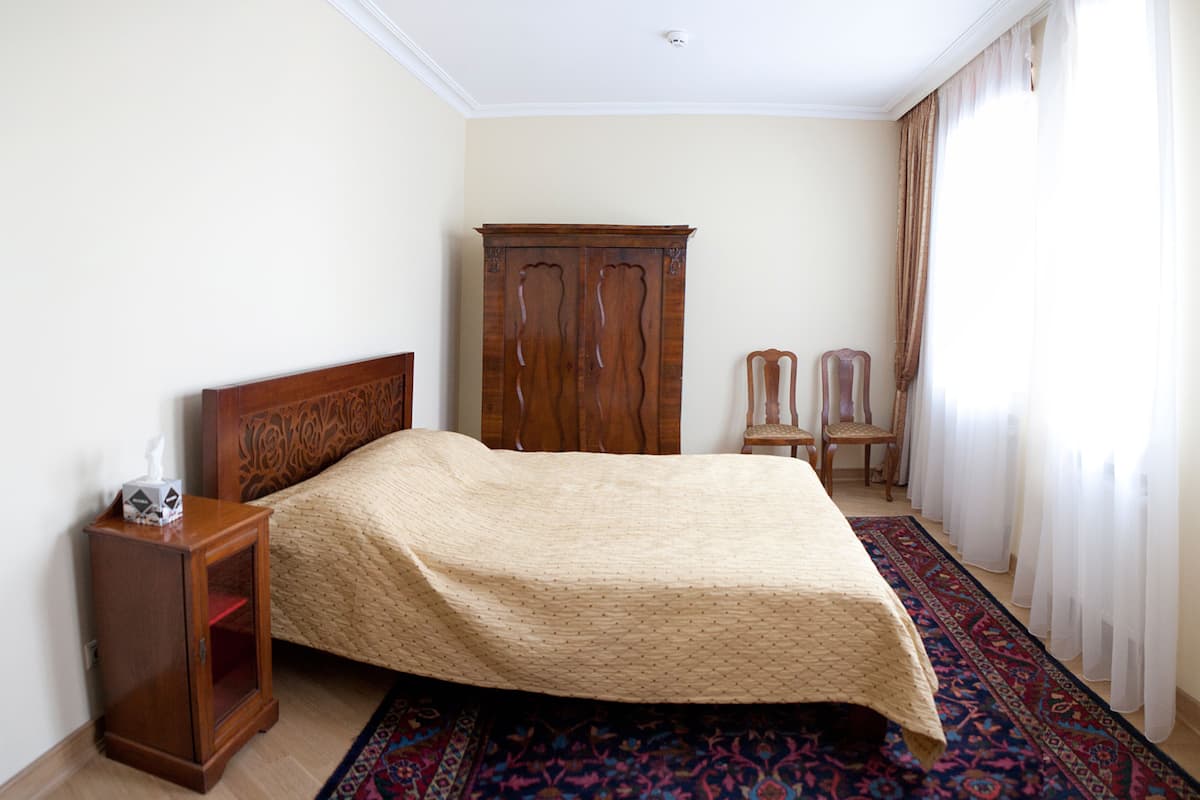Un dormitorio con una cama de madera, una mesita de noche, un armario y una silla.