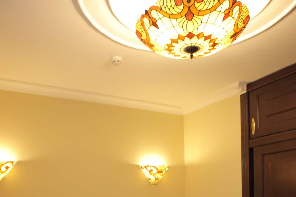Una cama bien tendida con sábanas blancas en una habitación con cabecera de madera y una lámpara decorativa en el techo.