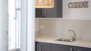 Una cocina moderna con un lavaplatos empotrado, armarios oscuros y una lámpara colgante de mimbre.