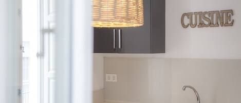 Una cucina moderna con lavello integrato, mobili scuri e una lampada a sospensione in vimini.
