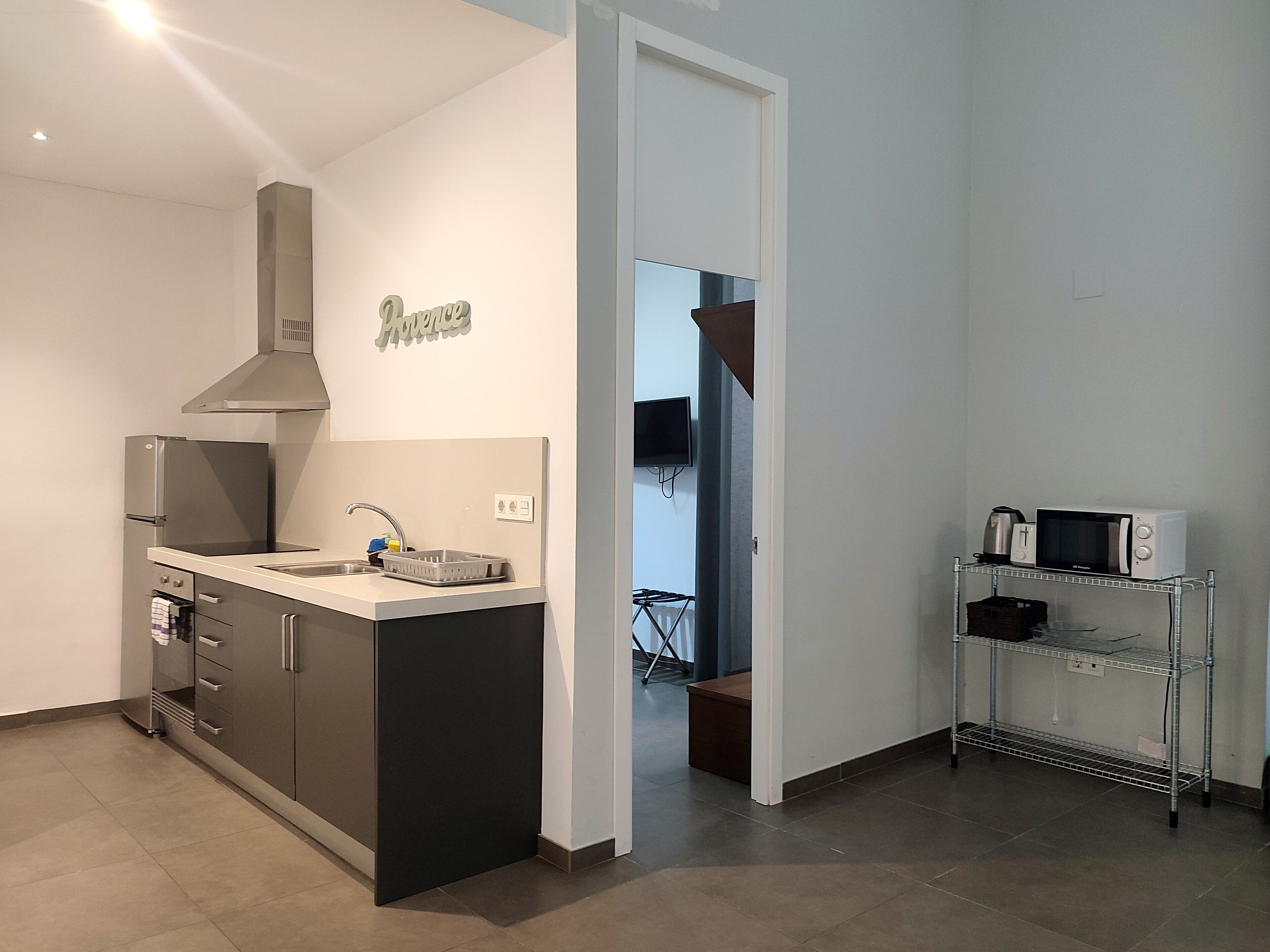A modern kitchen with a built-in oven, a sink, and a stainless steel refrigerator.