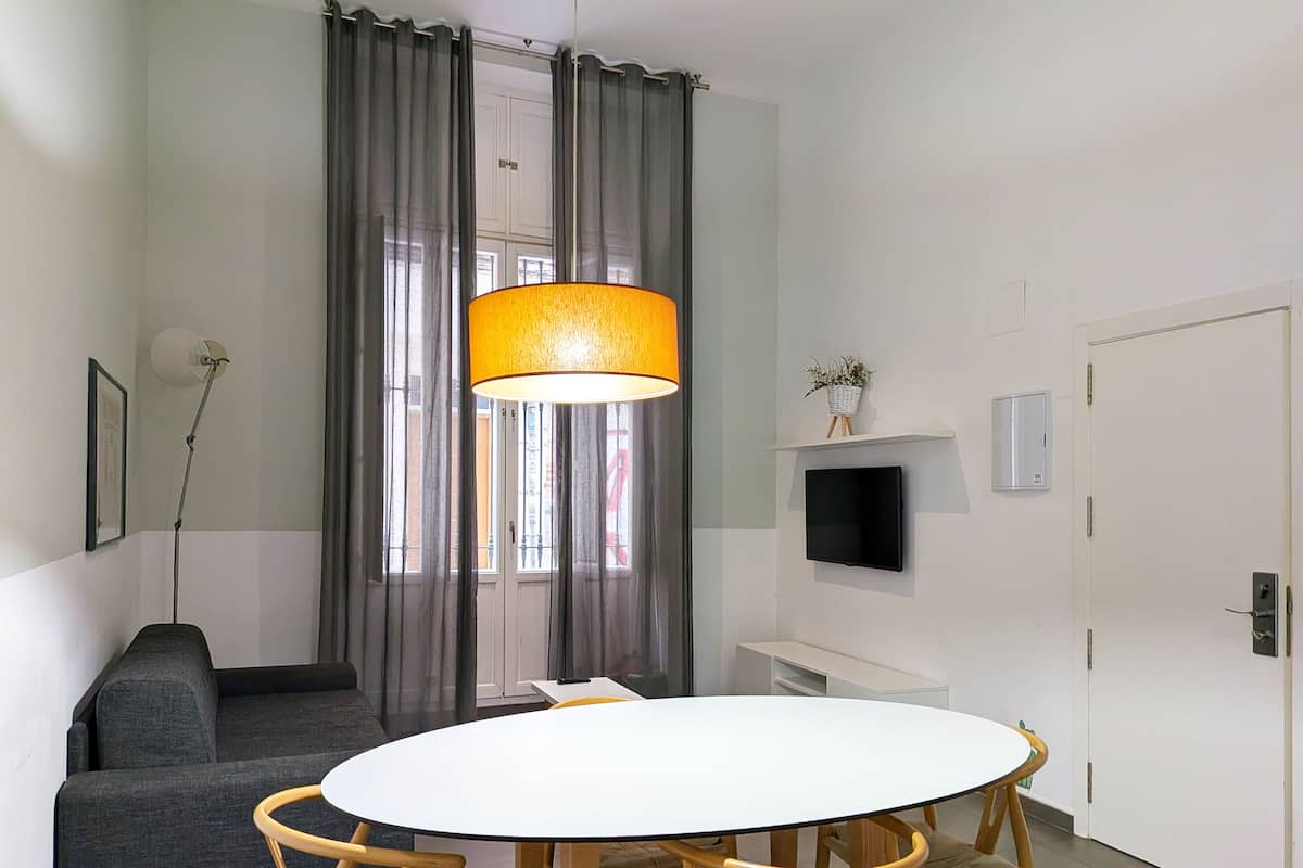A modern living room with a round white table, grey sofa, and a large floor lamp.