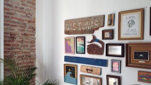 Una pared con varias obras de arte enmarcadas y un cartel rústico.