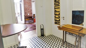 Una zona de recepción con piso a cuadros, un mostrador y una puerta que indica 'RECEPTION'.