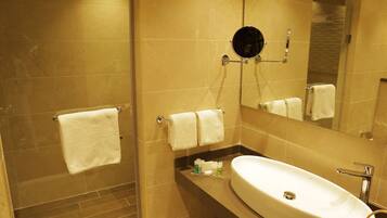 Une salle de bain avec un grand miroir, un lavabo et un espace douche.