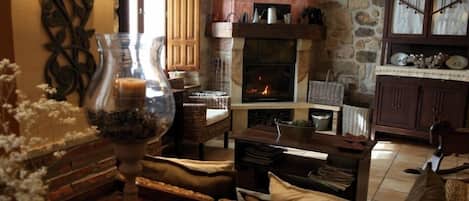 A cozy living room with a fireplace, wicker furniture, and decorative items.