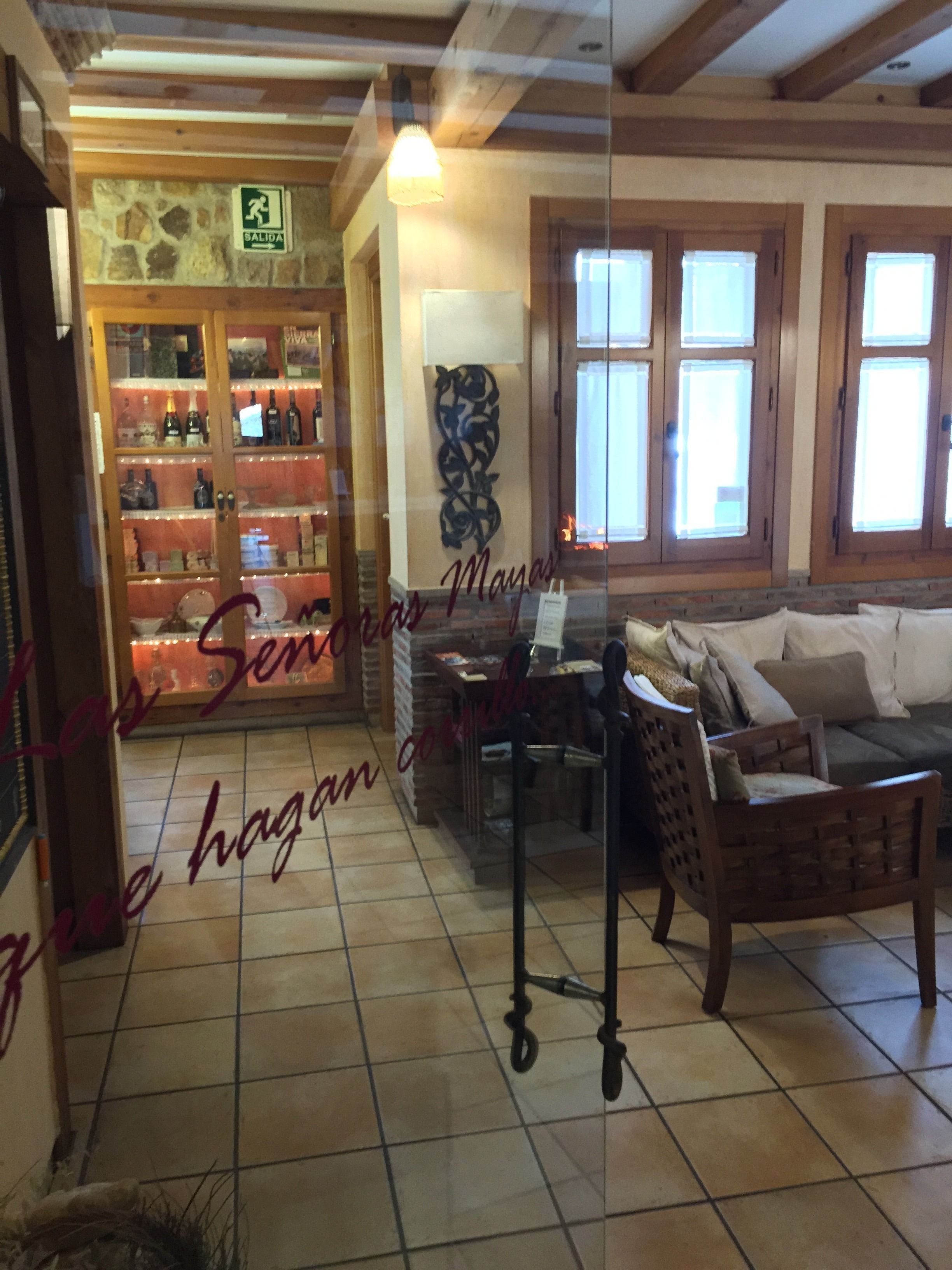 A cozy interior with a wooden ceiling, a stone wall, a bar area with bottles, a sofa, and a decorative wall piece.