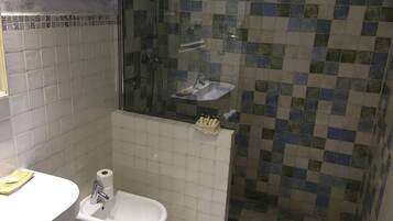 Un baño con ducha, lavamanos y bidé.