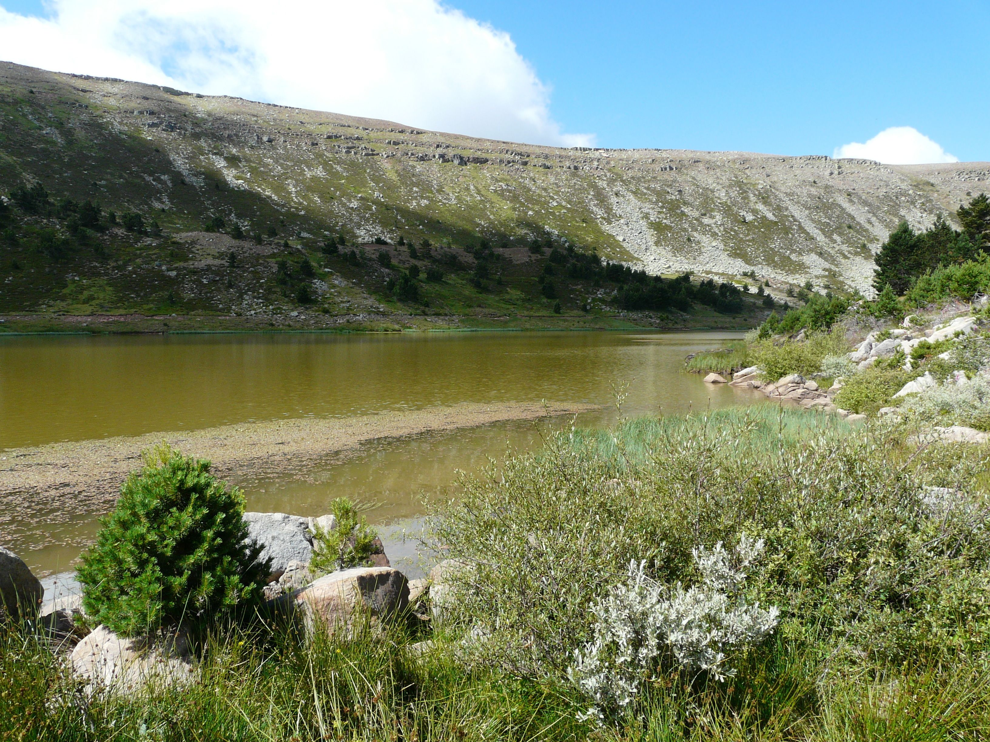 A natural landscape with a lake, rocky terrain, and sparse vegetation.