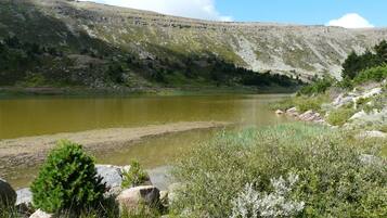A natural landscape with a lake, rocky terrain, and sparse vegetation.
