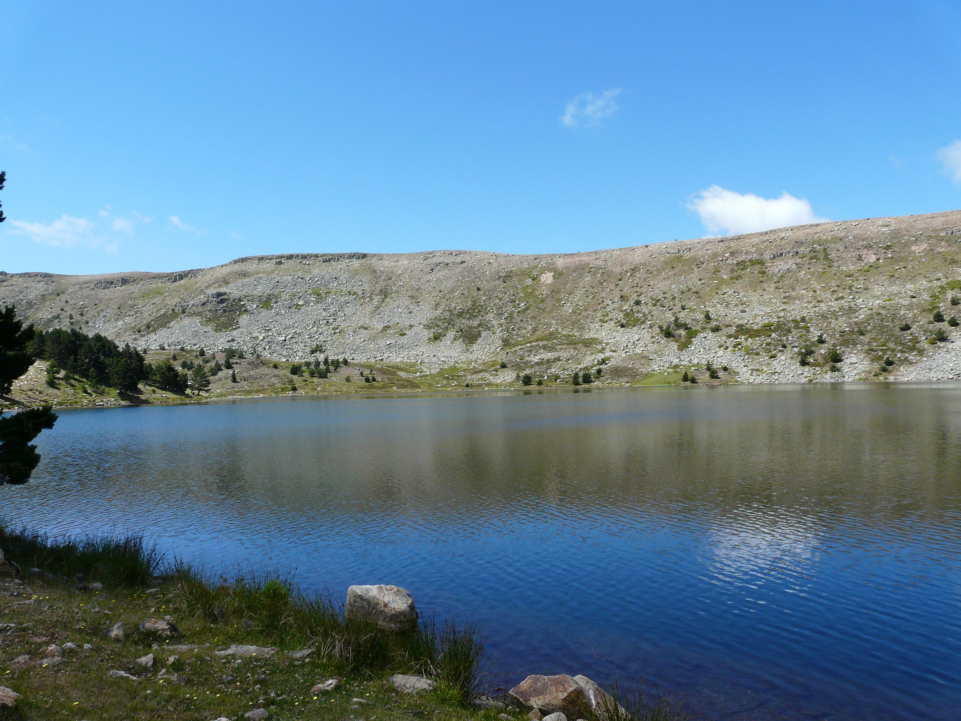 Ein ruhiger See, umgeben von felsigen Hügeln und spärlicher Vegetation.