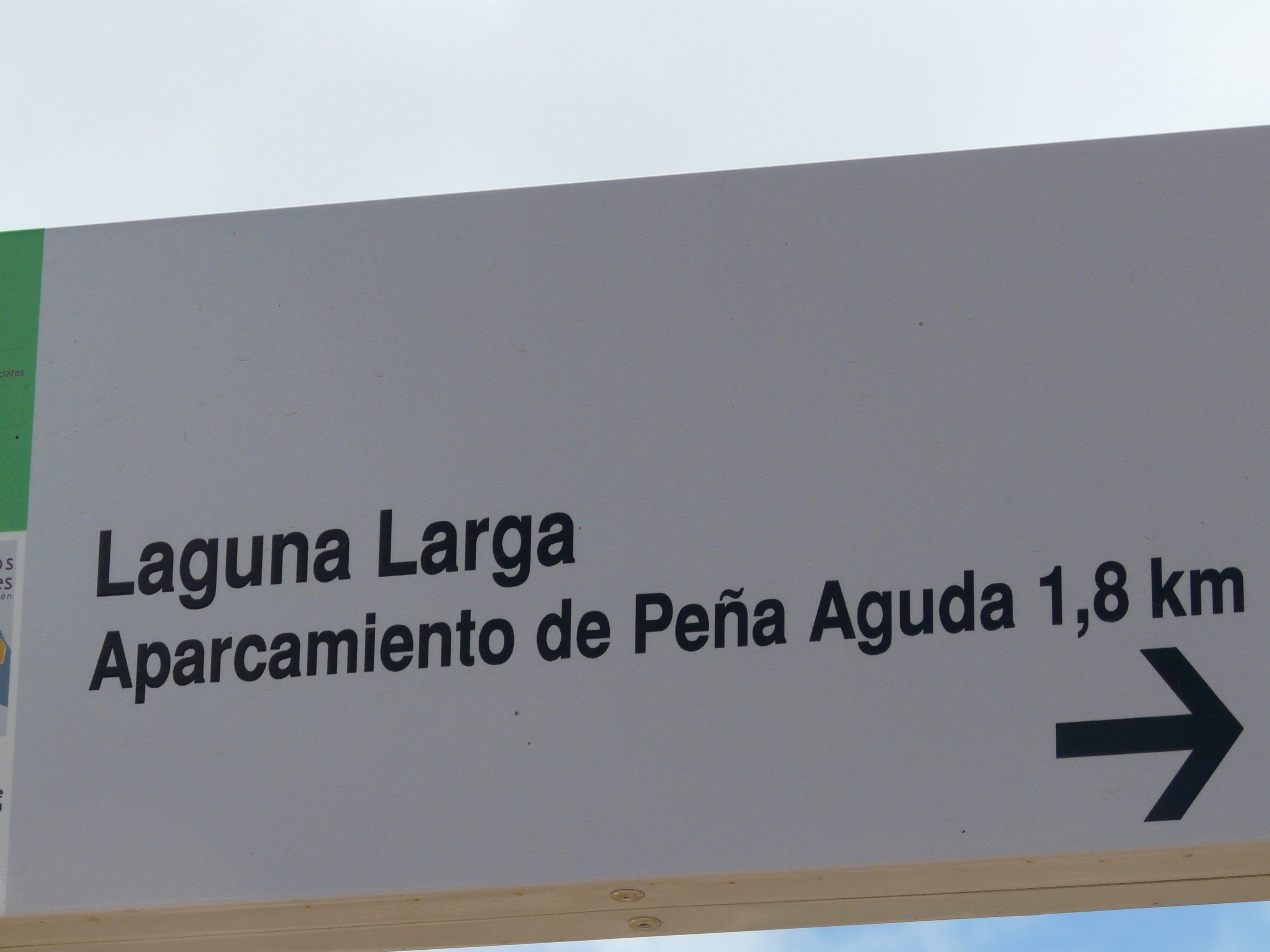 A directional sign indicating 'Laguna Larga' and 'Aparcamiento de Peña Aguda' 1.8 km to the right.