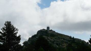 Una colina rocosa con una pequeña torre en la cima, rodeada de árboles.