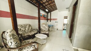 A spacious room with a high ceiling, a dining area with a table and chairs, and a patterned sofa set. - MDJ Suites (Cabo Frio)