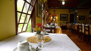 Comedor con mesas dispuestas para una comida, con vistas amplias a través de grandes ventanales.