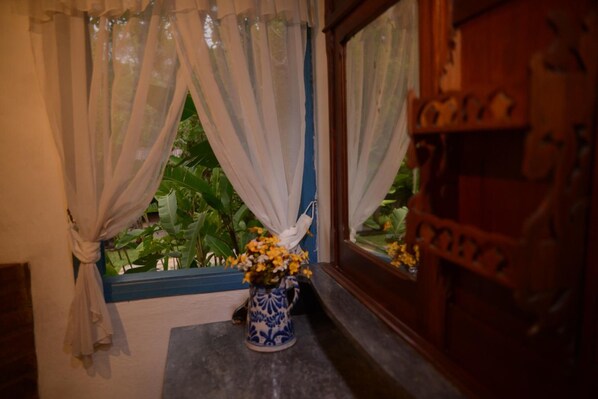A window with sheer curtains, a vase with yellow flowers, and a wooden cabinet. - Hotel Pousada Esmeralda (Itatiaia)