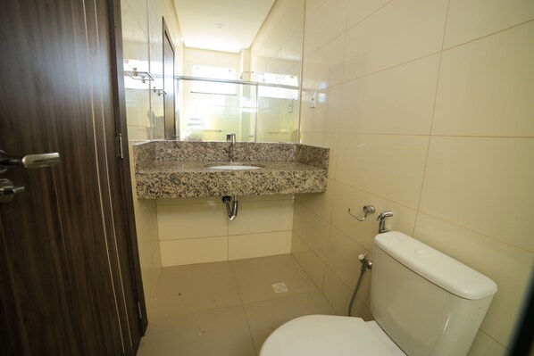 Baño con lavamanos de encimera de granito, inodoro y ducha.