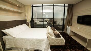 Un dormitorio moderno con una cama grande, un sofá, un televisor y vistas al mar.